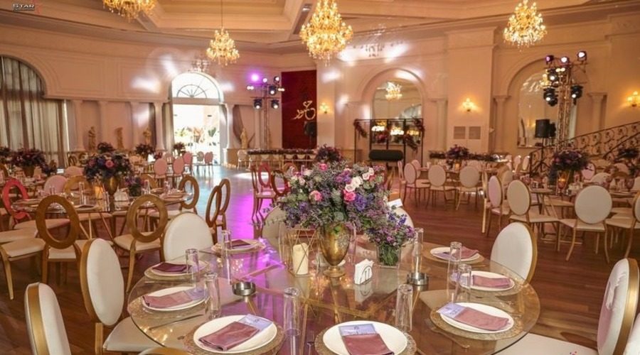 Banquet tables laid with floral centrepieces beneath the ballroom chandeliers