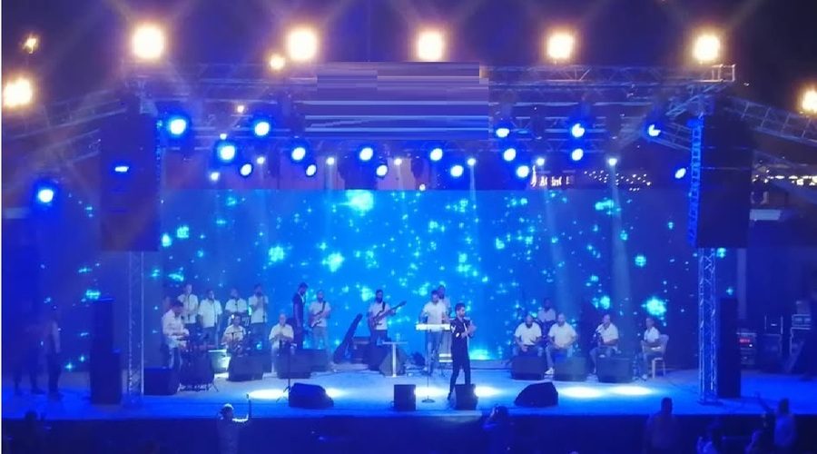 Performers on the outdoor stage under blue lighting