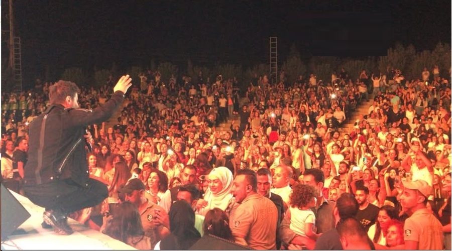 A singer at the edge of the stage facing a full crowd